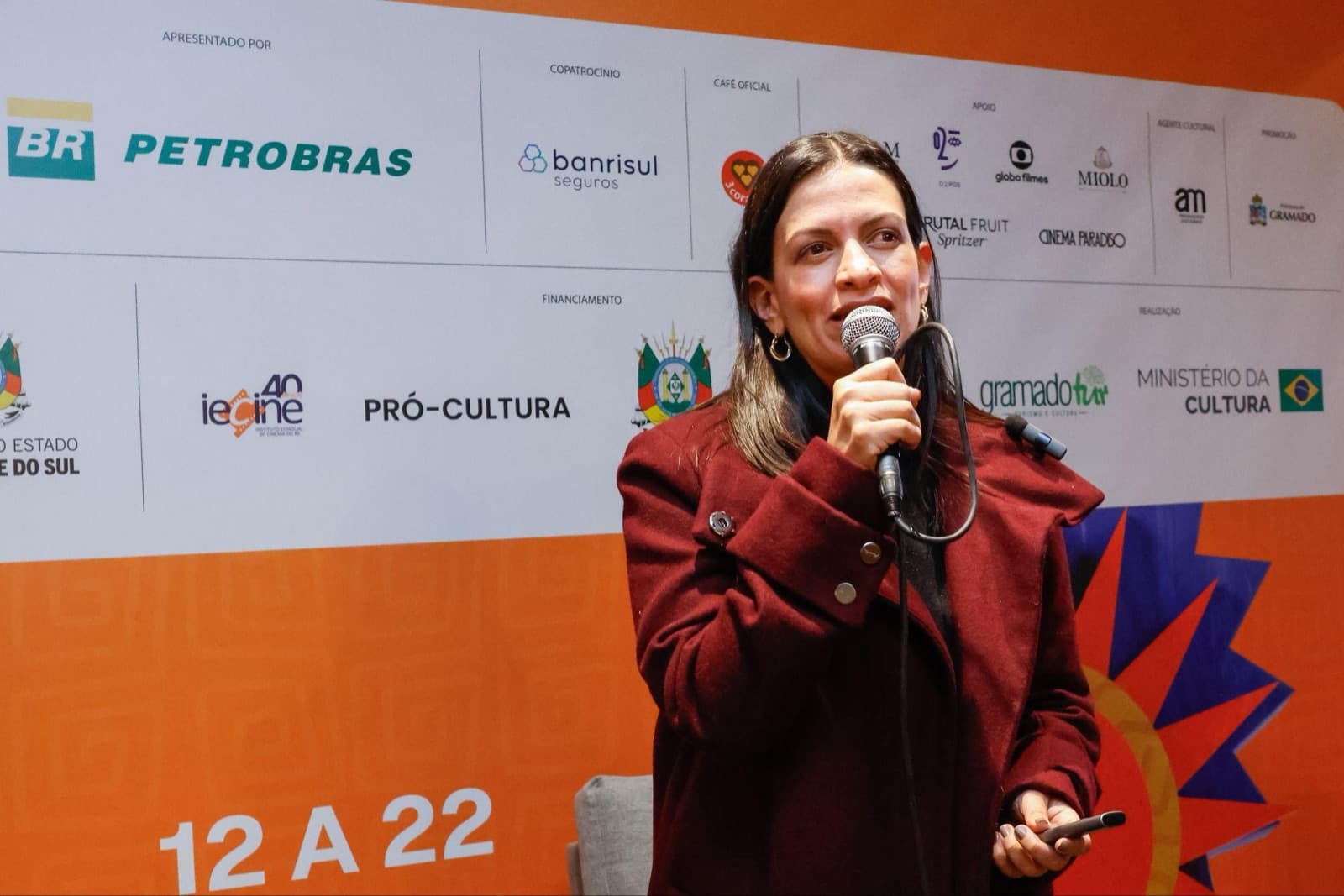 Maria Fernanda Galeano Rojo, secretária de Desenvolvimento Econômico de Medellín, fala ao microfone diante do painel de patrocinadores do Festival