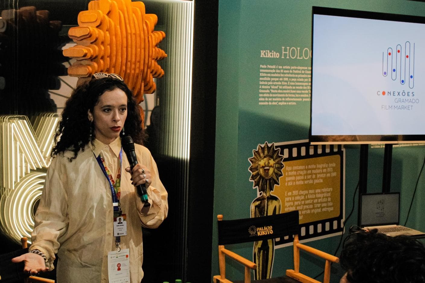 Palestrante durante atividade do Conexões Gramado Film Market, ao lado de painel do Kikito