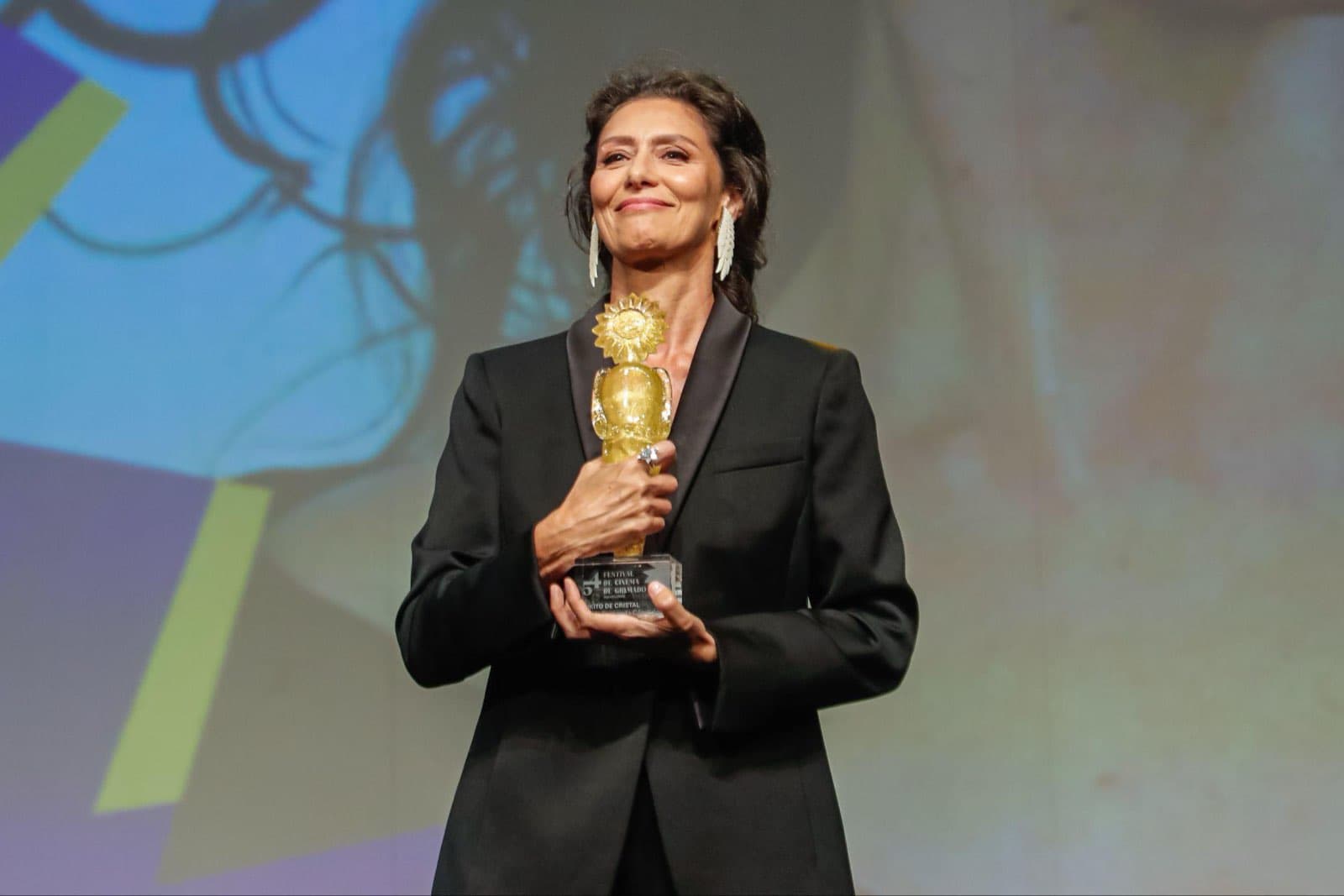 Maria Fernanda Cândido no palco do Palácio dos Festivais segurando o Troféu Kikito de Cristal